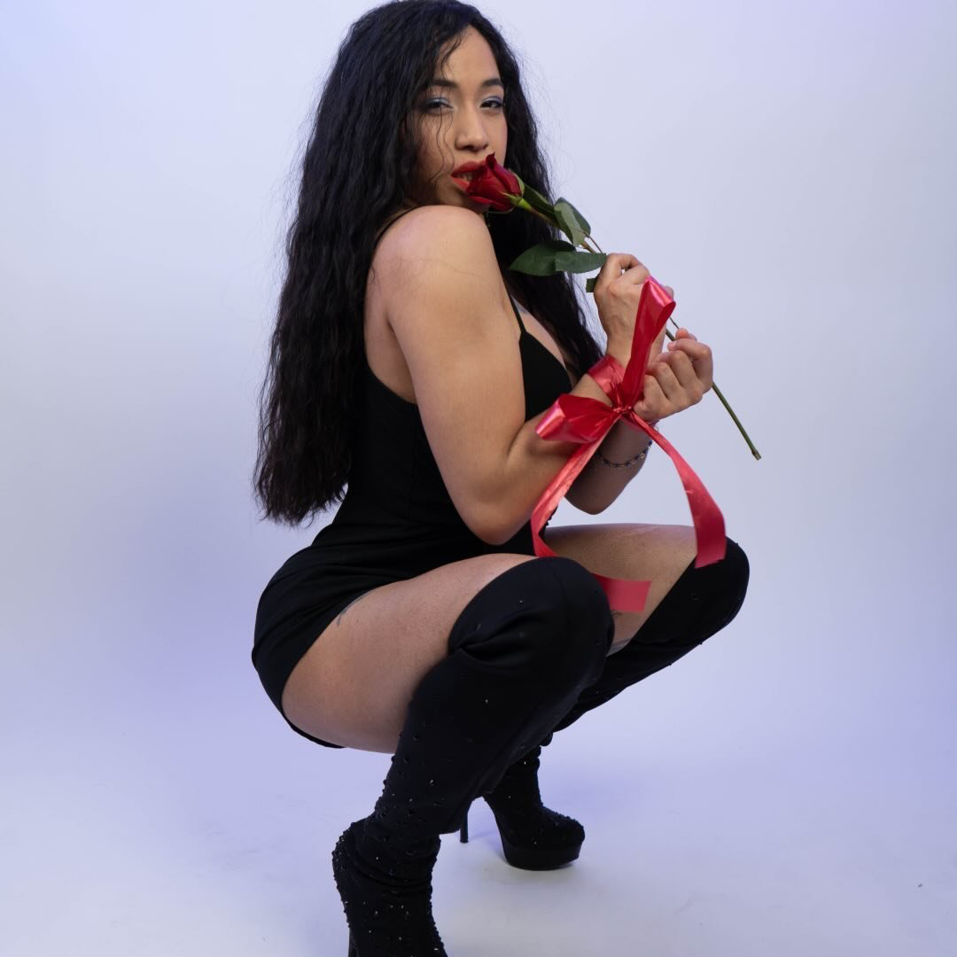 Esperanzalety Christie Matos holding a red rose with red ribbon in a studio portrait